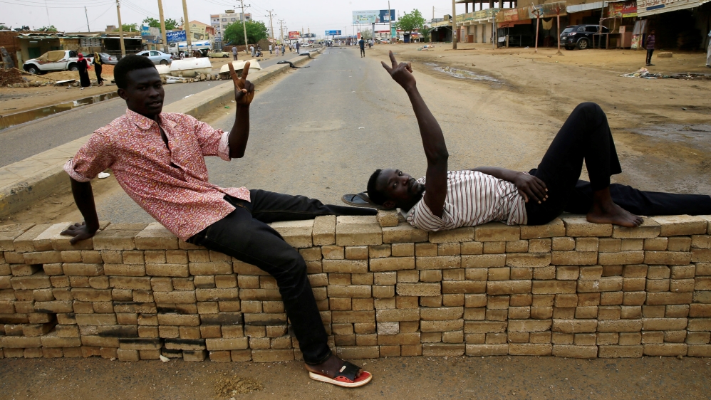 Sudanese protesters rest on bricks used to barricade a street, demanding that the country's Transitional Military Council handover power to civilians, in Khartoum