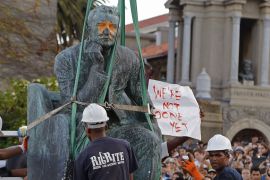 Students surround the bronze statue of British colonialist Cecil Rhodes, as it is removed from the campus of Cape Town University, South Africa on April 9, 2015 [File:AP/Schalk van Zuydam]