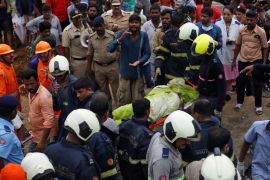Rescue workers carry the body of a victim after a wall collapsed on shanties due to heavy rains at a slum in Mumbai