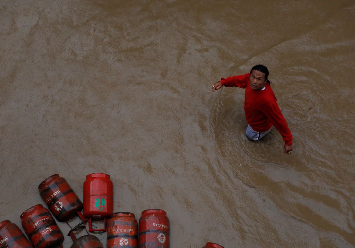 A man walks past gas cylinders in a flooded colony in Kathmandu, Nepal July 12, 2019. REUTERS/Navesh Chitrakar