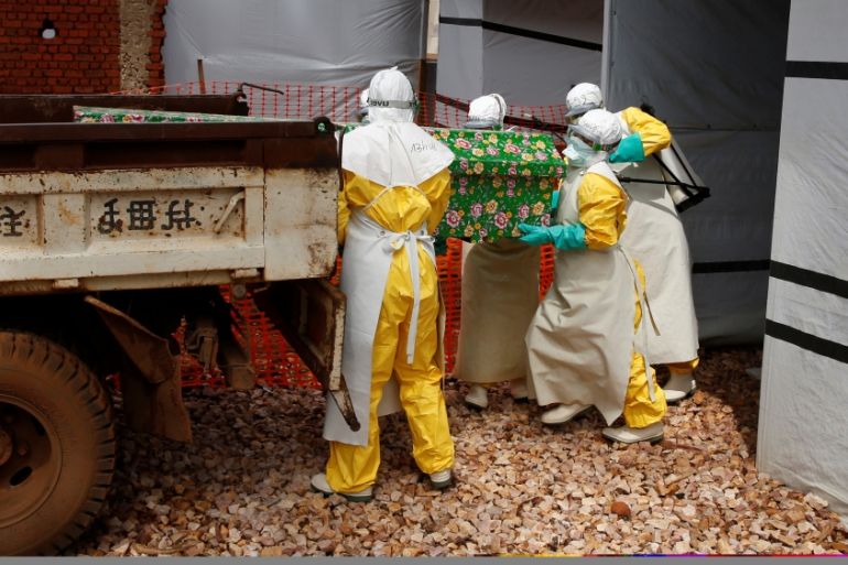 Health workers dressed in Ebola protective suits place a coffin containing the body of an Ebola patient to a truck at an Ebola treatment centre in Butembo