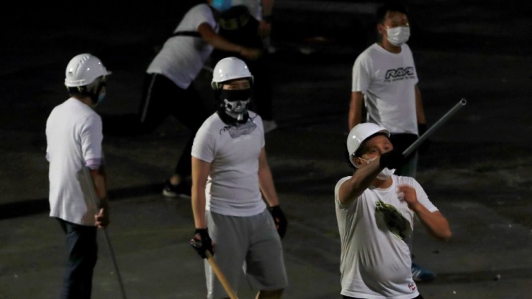Men in white T-shirts with poles are seen in Yuen Long after attacked anti-extradition bill demonstrators at a train station, in Hong Kong, China July 22, 2019