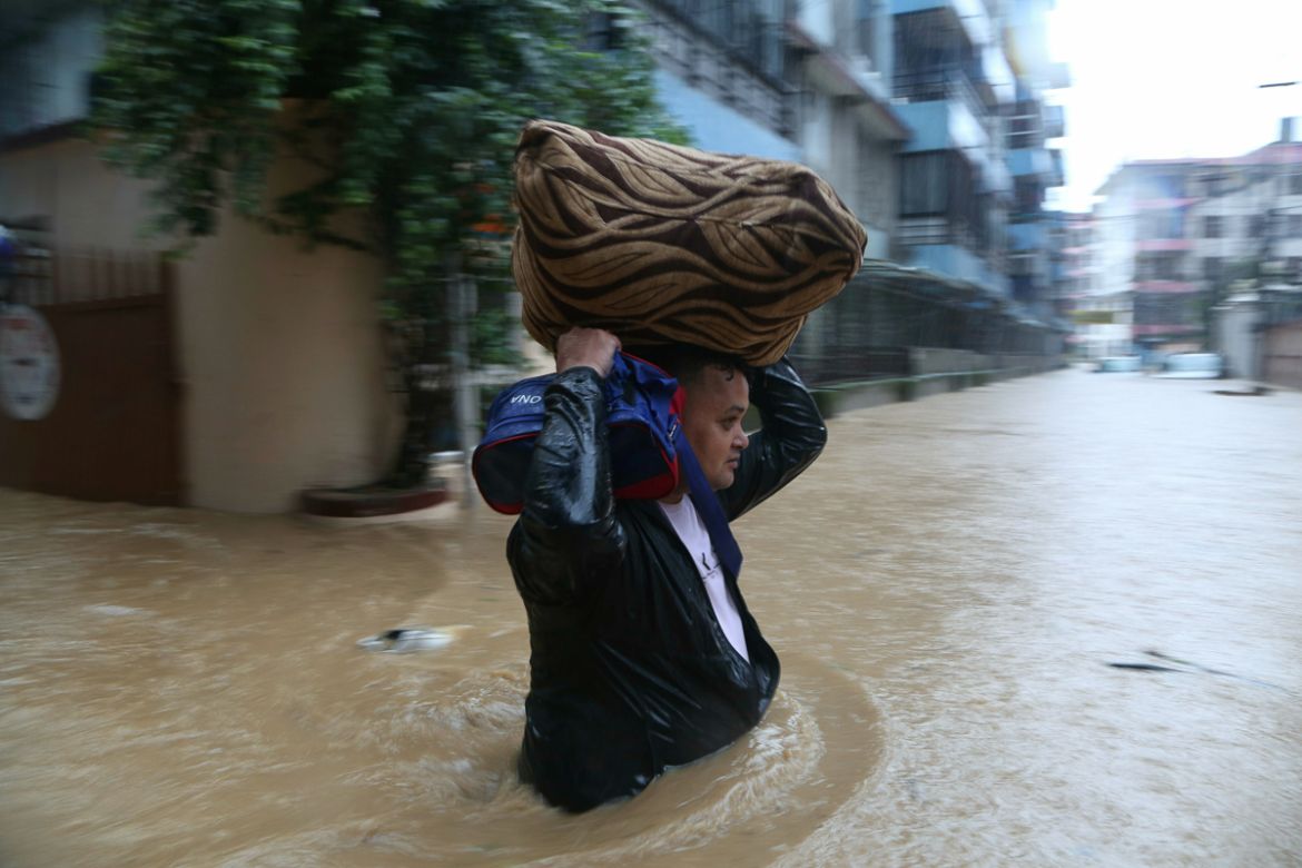 A Nepalese man wades with his belonging through a flooded street in Kathmandu, Nepal, Friday, July 12, 2019. Heavy rainfall since Thursday night has caused havoc throughout the country. According to t