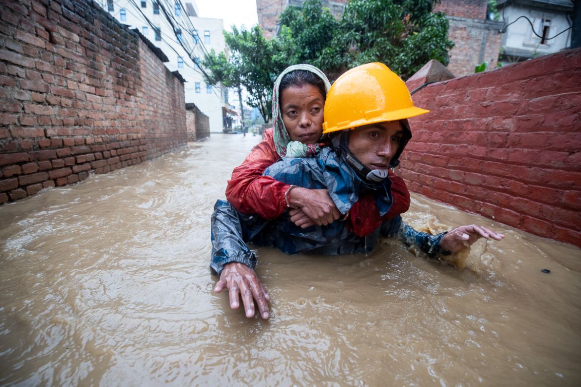 A rescuer carries a woman from flooded houses following torrential rains in Kathmandu, Nepal, 12 July 2019. Meteorologists warned of heavy monsoon rains in Nepal that put several parts of the country