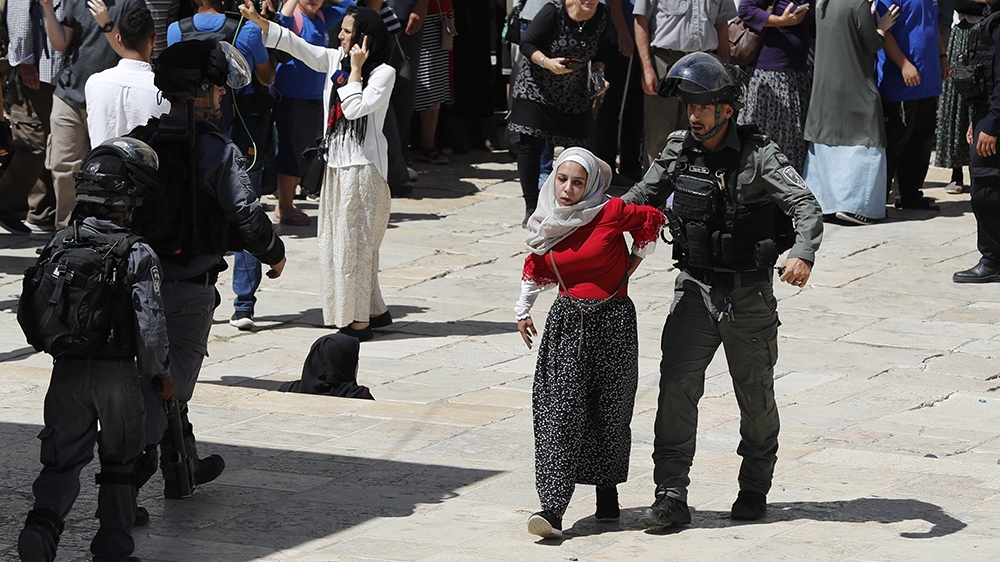 A member of the Israeli security forces restrains a Palestinian girl during clashes that broke out at the al-Aqsa Mosque compound in the Old City of Jerusalem on August 11, 2019, during the overlappin