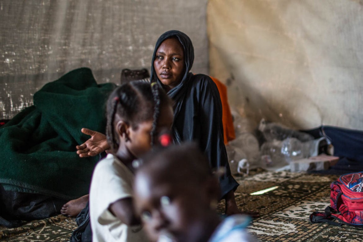 A woman with her children sit and rest in a tent of the improvised IDP camp in Tripoli.