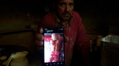 In this Monday, Aug. 26, 2019, photo, a Kashmiri baker Sonaullah Sofi displays a photograph of his son after he was allegedly tortured by Indian army soldiers at their bakery in the southern village o