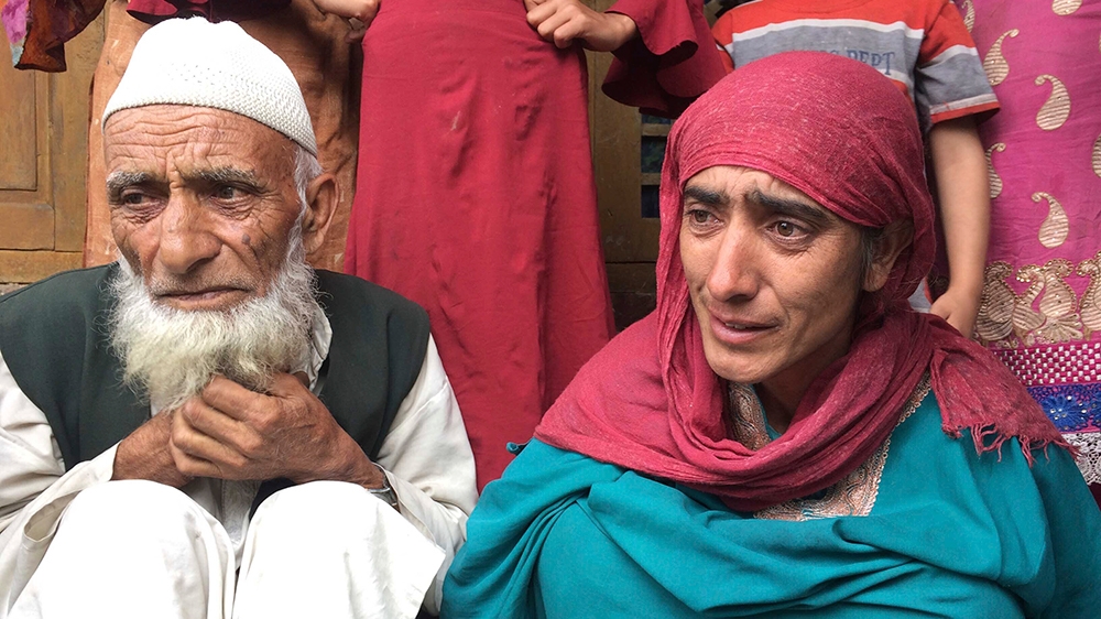 In this Monday, Aug. 26, photo, A Kashmiri man Mohammed Abdullah sits with his daughter at their home and talks to reporters about his grandson who was picked up in a nocturnal raid recently and shift
