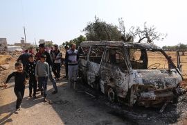People look at a destroyed van near the village of Barisha, in Idlib province, Syria, Sunday, Oct. 27, 2019, after an operation by the U.S. military which targeted Abu Bakr al-Baghdadi, the shadowy le