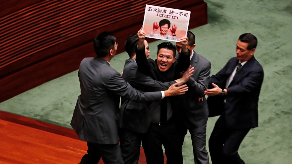 Pro-democracy lawmaker Wu Chi-wai holding a placard is escorted by security from the Legislative Council, as Hong Kong's Chief Executive Carrie Lam takes questions from lawmakers