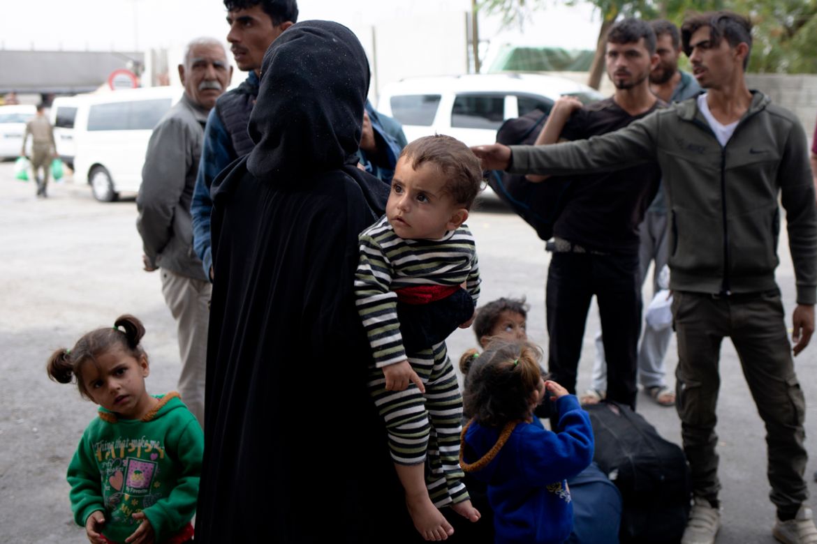 Families wait to board designated buses at the Karkamis border crossing to return to their homes across southern Turkey