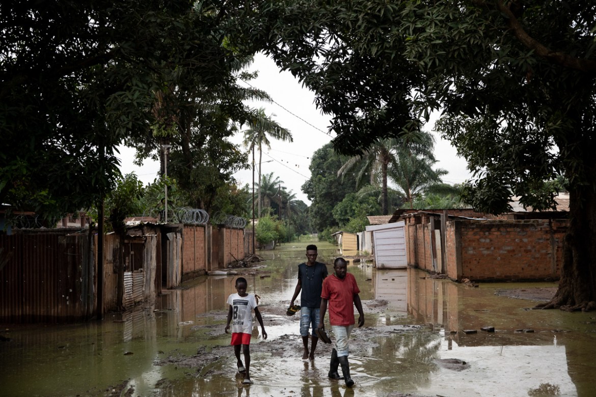 Parfait Madigoto (in red) and two younger neighbours walk in their inundated street, in Bimbo neighbourhood. “Water raised little by little. One morning, we saw it was already inside the house. I got