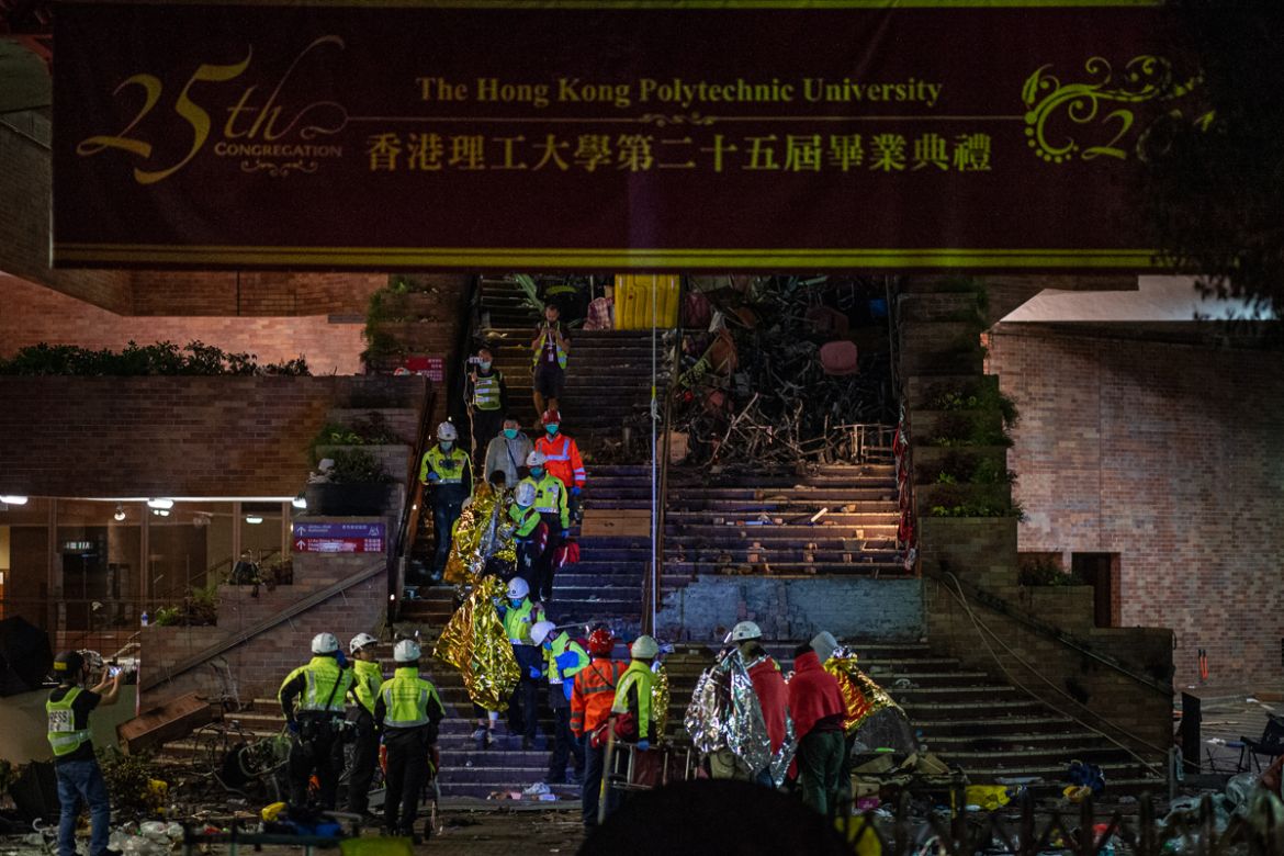 Unwell and injured protesters wrapped in emergency thermal blankets leave the campus helped by medics (yellow vests) at the main entrance of the Hong Kong Polytechnic University in the Hung Hom distri