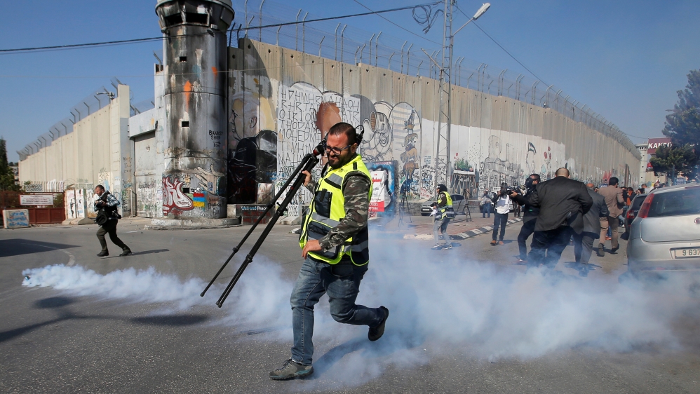Palestinian journalist runs away from tear gas fired by Israeli forces during a protest to show solidarity with his colleague Muath Amarna, who was shot in his eye, in Bethlehem