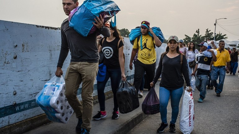 Venezuelans carry bags of supplies while crossing the Simon Bolivar International Bridge near the Venezuelan border in Cucuta, Colombia, on Tuesday, March 26, 2019