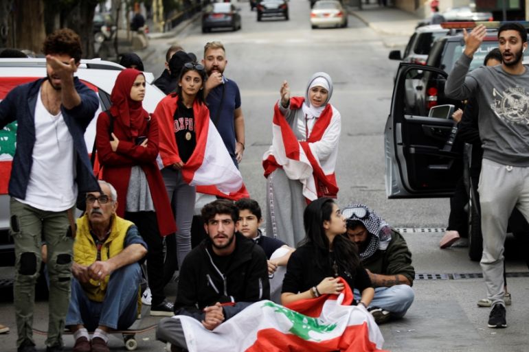 Protesters gesture towards a driver at a roadblock during ongoing anti-government demonstrations in Beirut