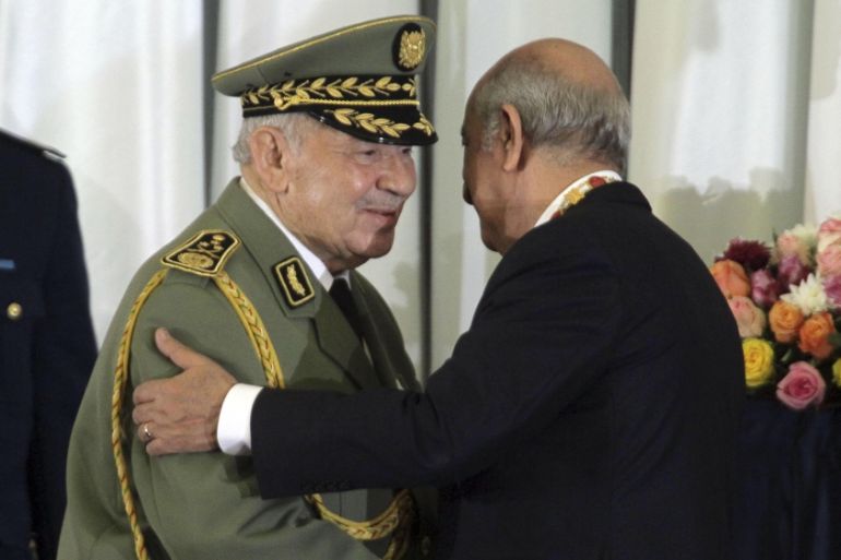In this photo taken Thursday, Dec. 19, 2019, Algerian military chief Gaid Salah, left, embraces president Abdelmajid Tebboune during an inauguration ceremony in the presidential palace, in Algiers, Al