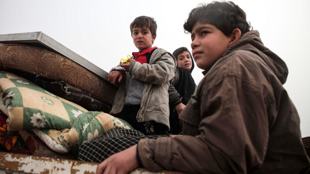 Syrian children look on while riding in the back of a truck as part of a convoy of people from the south of Idlib province fleeing bombardment by the government and its allies on the northwestern regi