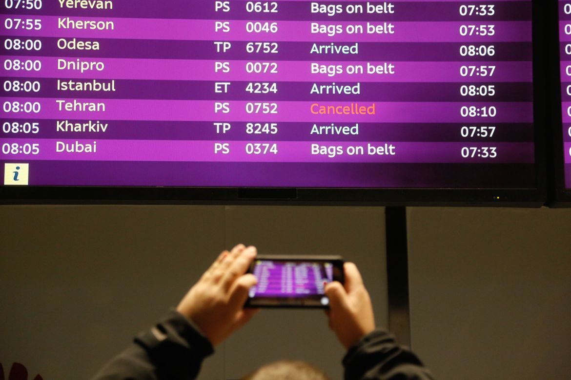 A man takes a photo of the arrivals board with the cancelled fight from Tehran after Ukrainian 737-800 plane crashed on the outskirts of Tehran, Iran, at Borispil international airport outside Kyiv, U