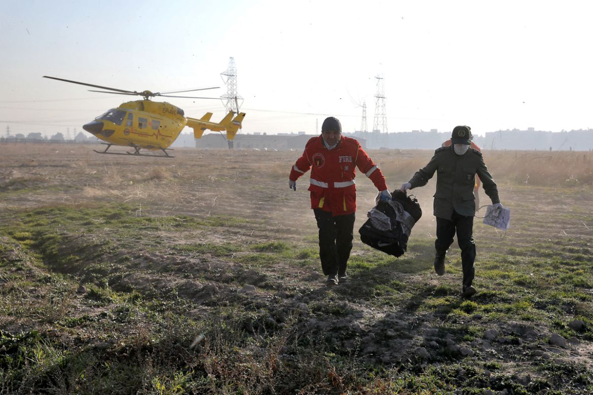Rescue workers carry items retrieved from the scene where a Ukrainian plane crashed in Shahedshahr, southwest of the capital Tehran, Iran, Wednesday, Jan. 8, 2020. A Ukrainian airplane with more than