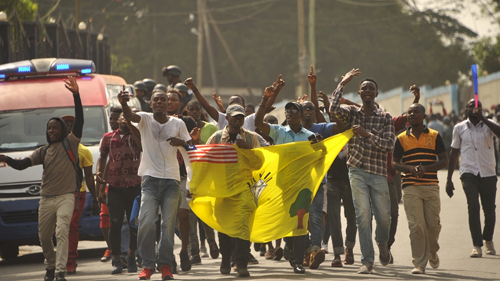 Members of the Council of Patriots (COP)  hold a flag as they protest outside Monrovia's Capitol building against the deepening economic crisis under Liberian President George Weah, in Monrovia on Jan