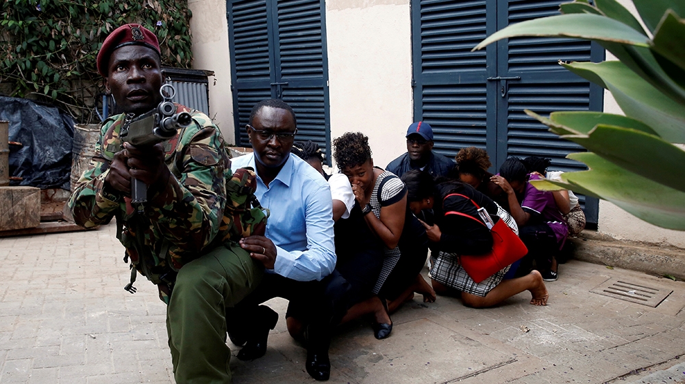 People are evacuated by a member of security forces at the scene where explosions and gunshots were heard at the Dusit hotel compound, in Nairobi, Kenya January 15, 2019. REUTERS/Baz Ratner