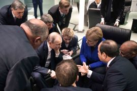 Russian President Vladimir Putin, German Chancellor Angela Merkel and other officials talk during a conference on Libya at the German Chancellery in Berlin on January 19, 2020 [AP]