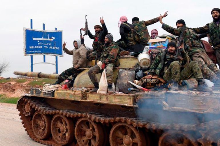 In this photo released Wednesday, Feb. 12, 2020, by the Syrian official news agency SANA, Syrian government soldiers on a tank hold up their rifles and flash victory signs, as they patrol the highway