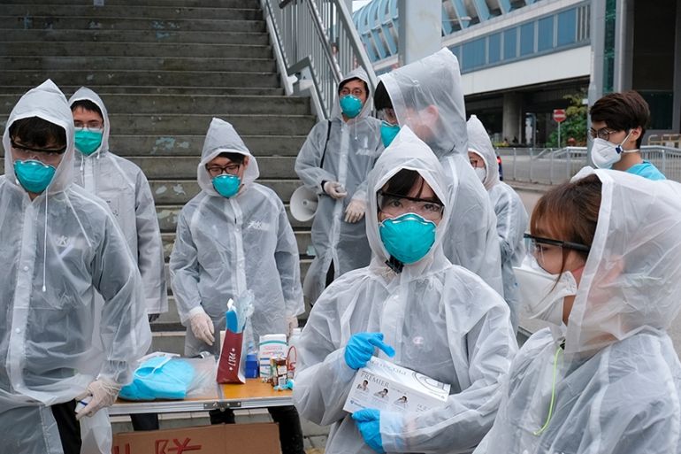 Residents wearing masks and raincoats volunteer to take temperature of passengers following the outbreak of a new coronavirus at a bus stop at Tin Shui Wai, a border town in Hong Kong, China February
