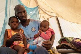 Kelvin Charamba with his daughters inside the tent the family has lived for the past year. [Tendai Marima/Al Jazeera]