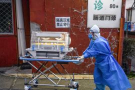A medical worker wears protective clothing as a preventive measure against the COVID-19 coronavirus as she pushes an incubator between buildings at a hospital in Beijing on February 21, 2020. An erupt