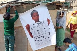 Asmat Ullat, 12, putting helping to put up a poster of his comic “My Dream” [Tasnim Nazeer/Al Jazeera]