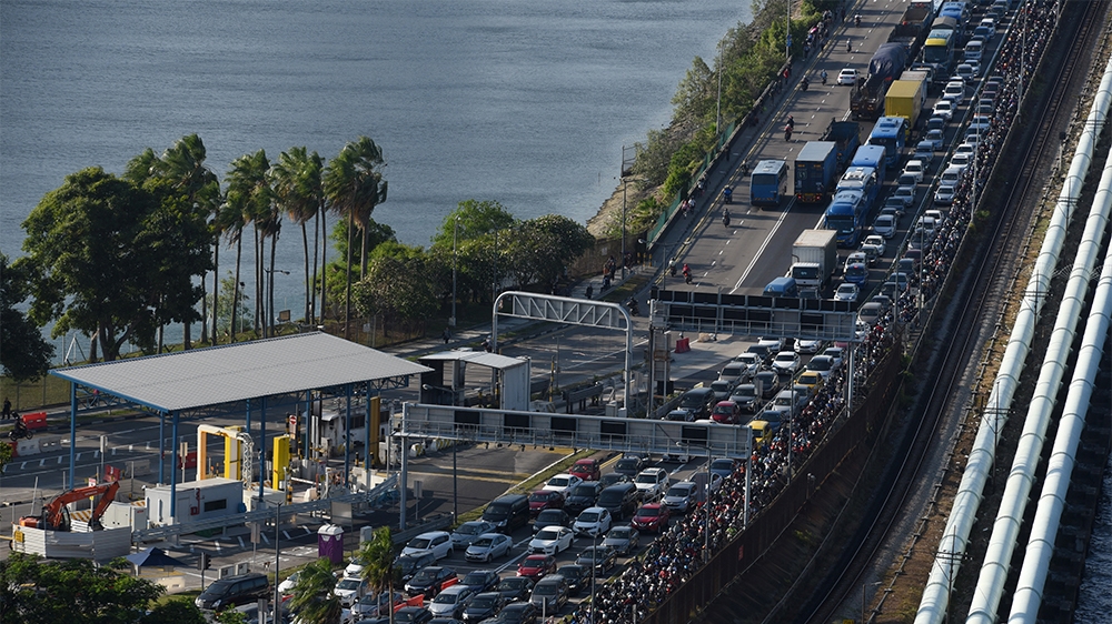 Vehicles form a long queue to enter Woodlands checkpoint in Singapore on March 17, 2020 from across the causeway of the southern Malaysian state of Johor. - Malaysia will ban its citizens from travell