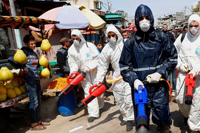 Workers wearing protective gear spray disinfectant as a precaution against the coronavirus, at the main market in Gaza City, Thursday, March 19, 2020. The Middle East has some 20,000 cases of the viru