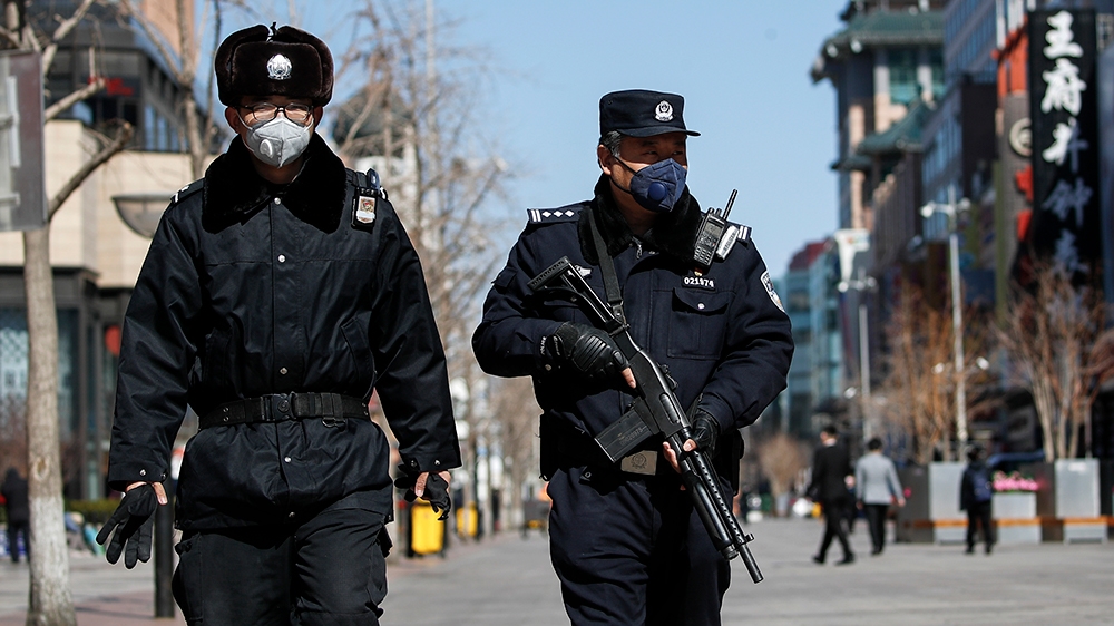 Policemen wearing protective face masks patrol the quiet Wangfujing shopping district following the coronavirus outbreak in Beijing, Tuesday, March 10, 2020. For most people, the new coronavirus cause