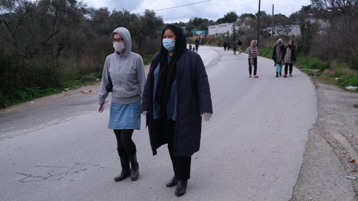 Migrants, wearing protective masks, walk outside the perimeter of the overcrowded Moria refugee camp on the northeastern Aegean island of Lesbos, Greece, Wednesday, March 11, 2020. For most people, th