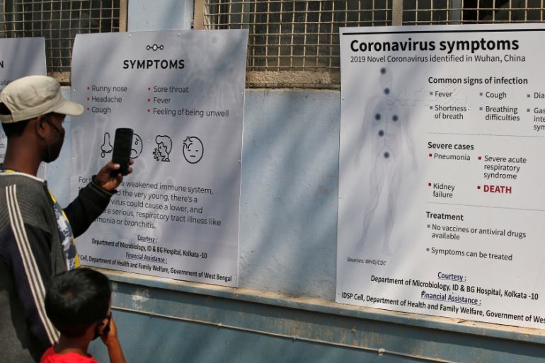 A man uses his mobile phone to take photographs of posters carrying messages on symptoms of coronavirus disease inside hospital premises in Kolkata