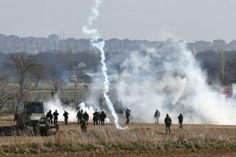 Greek riot police officers stand guard as tear gas is being fired near Turkey''s Pazarkule border crossing, in Kastanies