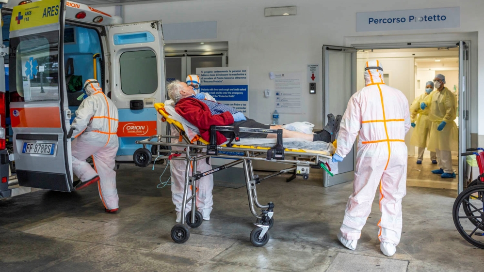 Medical workers in protective suits take an elderly coronavirus patient on a stretcher into an ambulance in the emergency room of the Gemelli Hospital, in Rome