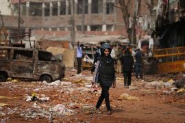 In this Thursday, Feb. 27, 2020, a television reporter holds a microphone as she walks through a street vandalized in Tuesday''s violence in New Delhi, India. Reporting in India has never been without