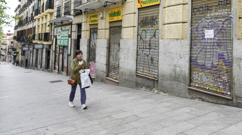 A pedestrian wearing a protective face mask walks by a shuttered outdoor equipment retailer in Madrid, Spain, on Monday, April 13, 2020. Italy, Spain and France reported a slowdown in new coronavirus