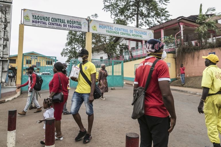 Some people wear masks as they walk by the entrance to the Yaounde General Hospital in Yaounde on March 6, 2020 as Cameroon has confirmed its first case of the COVID-19 coronavirus, a French national