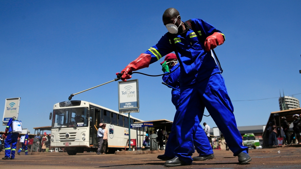 City health workers spray disinfectant at a bus terminus during a 21 day nationwide lockdown to limit the spread of coronavirus disease (COVID-19) in Harare