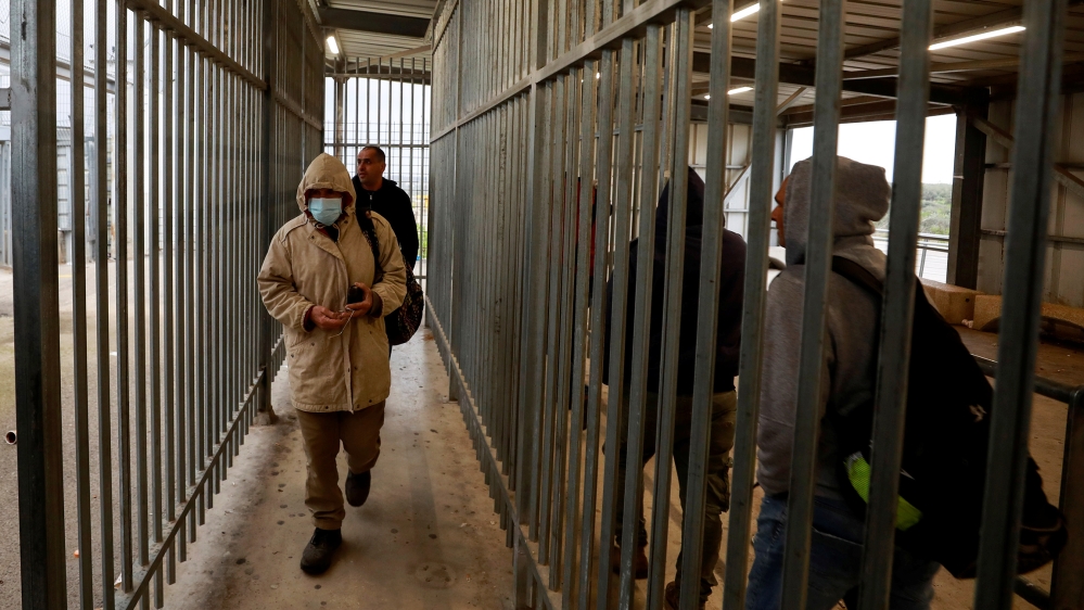 Palestinians working in Israel head to work through an Israeli checkpoint as the Palestinian Authority ordered them to stay at their workplaces over concerns of the spread of coronavirus disease, near