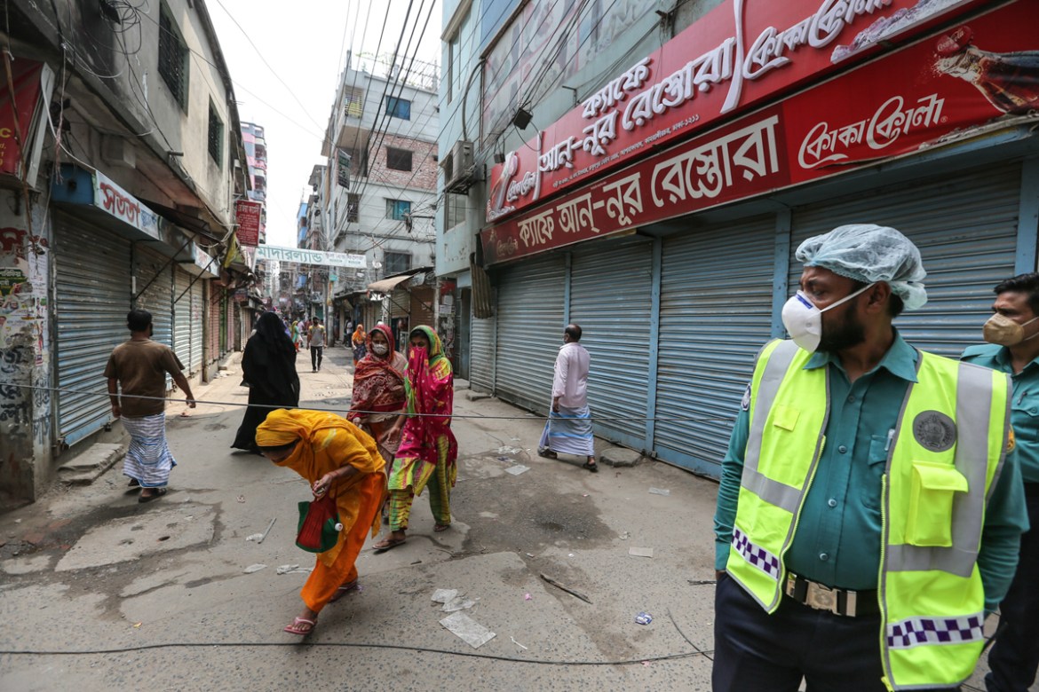 Police Men stand guard in front of an area put under lockdown as a precaution to stop the spread of coronavirus at Kamrangirchar, Dhaka. Mahmud Hossain Opu/Al Jazeera