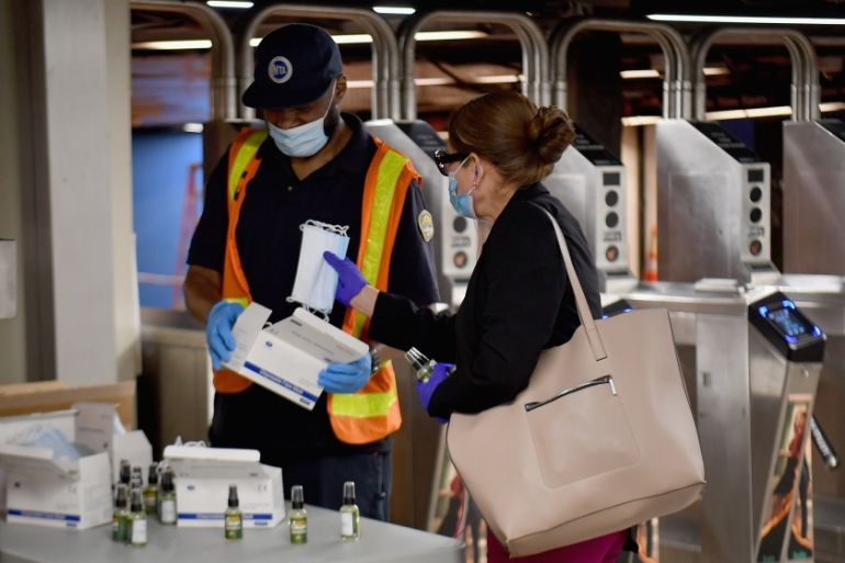 An MTA worker hands out free hand sanitizer and face masks at the Grand Central Station subway during morning rush hour on June 8, 2020 in New York City. Today New York City enters "Phase 1" of a four