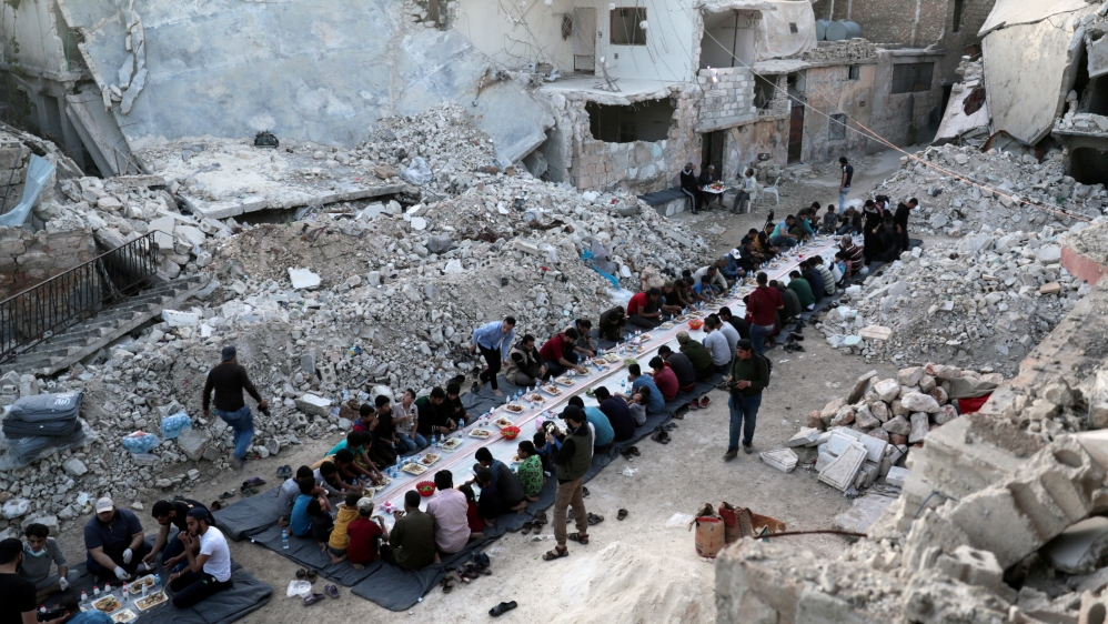 People eat their Iftar meal provided by a group of volunteers in a damaged neighbourhood, amid fear for the coronavirus disease (COVID-19) outbreak, in Atarib