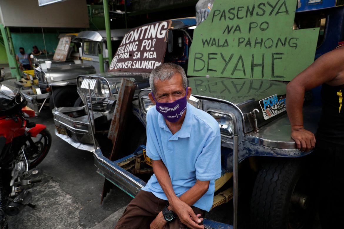 Driver Arthur Vinluan, 62, sits on a passenger jeepney beside a sign that says "sorry we''re not yet in operation" at the Tandang Sora terminal which have been home for them since a lockdown started th