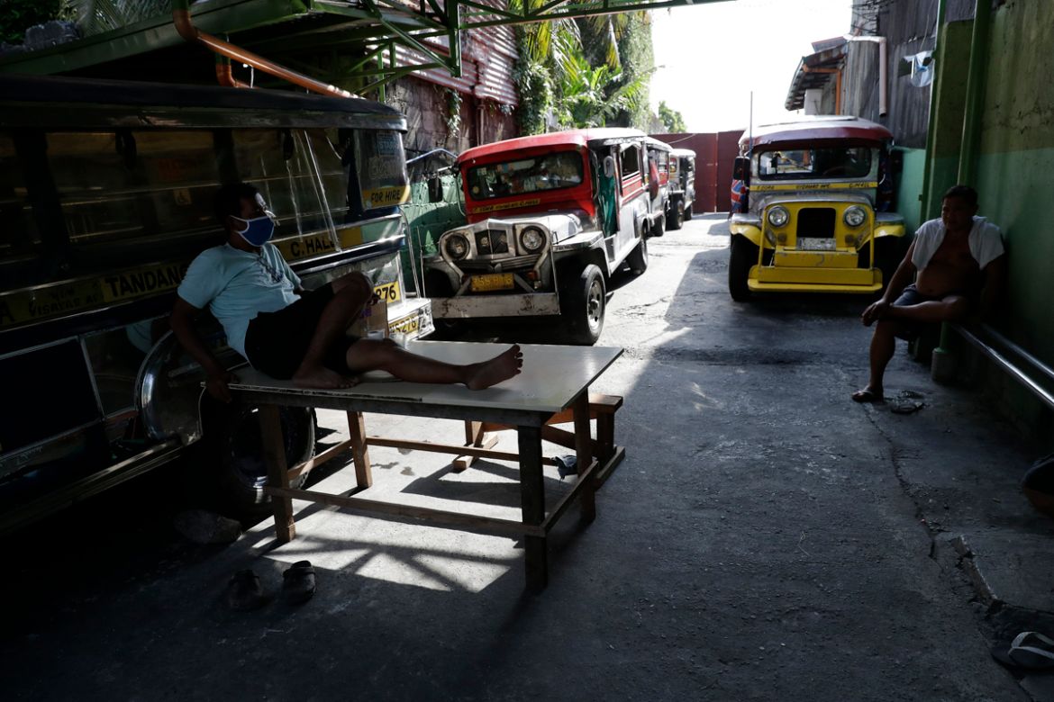 Driver Rey Escanilla, left, sits beside parked jeepneys at the Tandang Sora terminal which have been home for them since a lockdown started three months ago, on Wednesday, June 17, 2020 in Quezon city