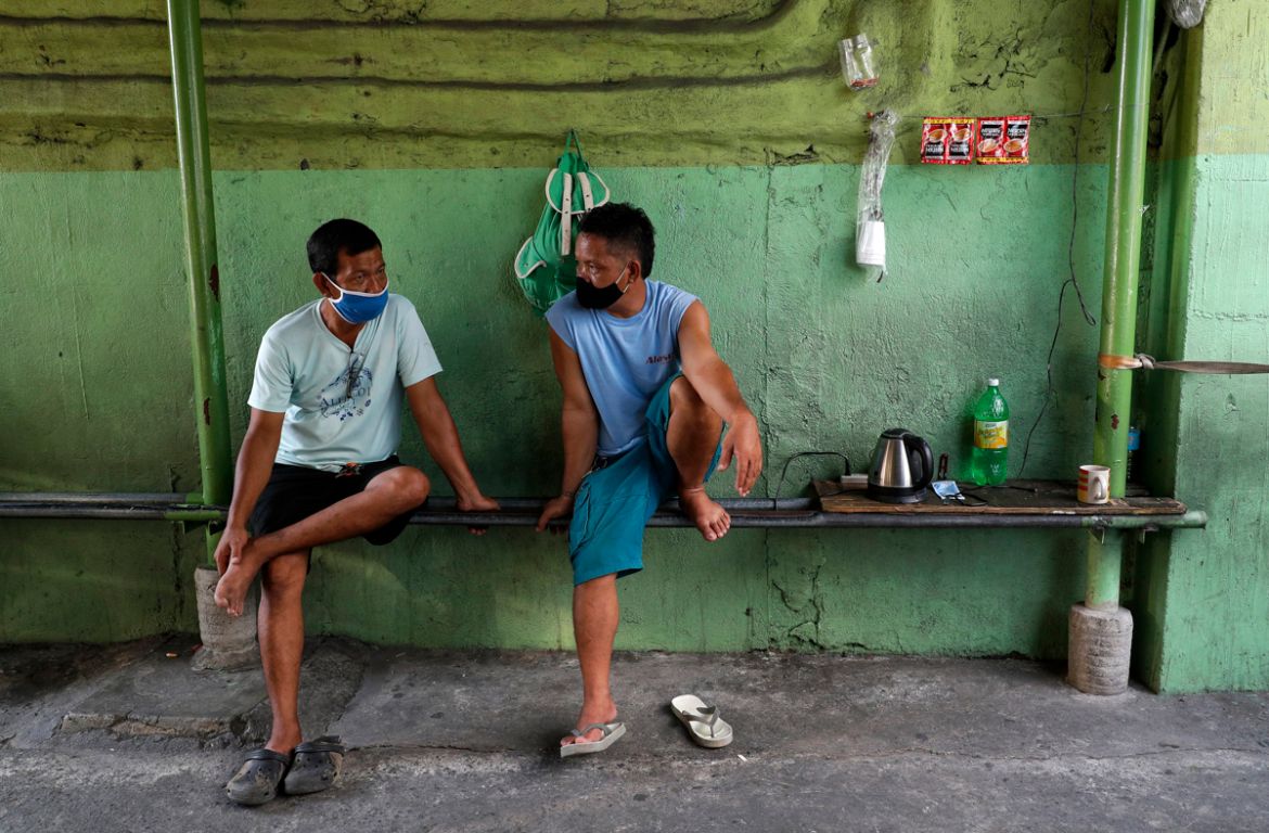 Jeepney driver Rey Escanilla, left, sits with another driver at their coffee station in the Tandang Sora terminal which have been home for them since a lockdown started three months ago, on Wednesday,